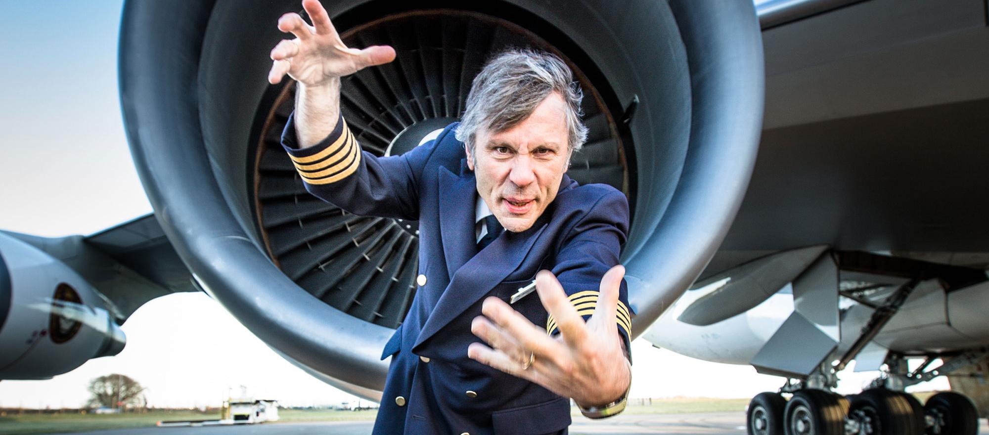 A close-up of Bruce Dickinson wearing a pilot suit in front of his Boeing  747-400 aircraft.